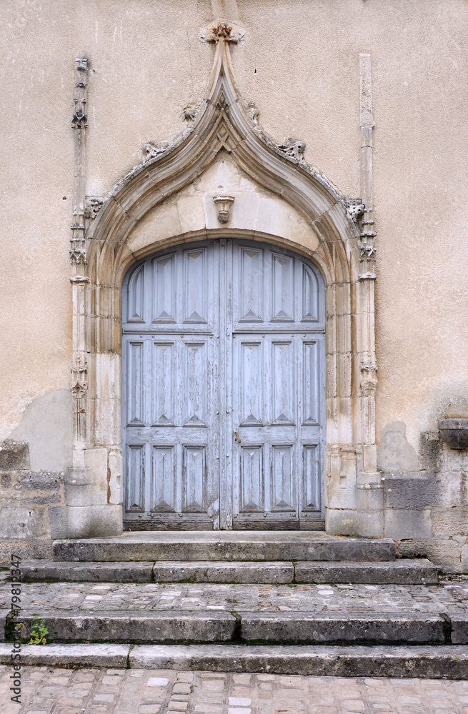 Stone portal and a wooden door to the medieval church in France.