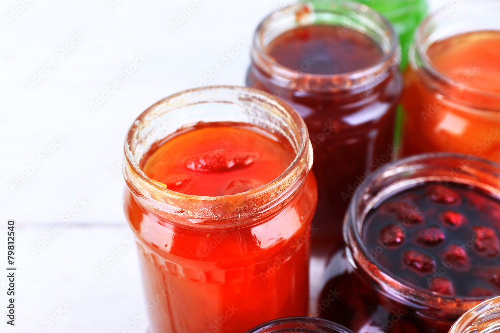 Homemade jars of fruits jam on color wooden planks background Homemade jars of fruits jam on color wooden planks background