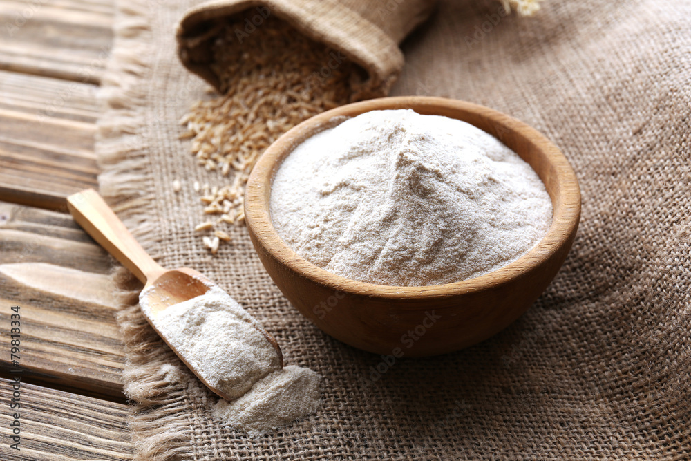 Flour in bowl with grains in bag on sackcloth background Flour in bowl with grains in bag on sackcloth background