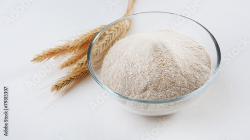 Glass bowl with flour and ears isolated on white