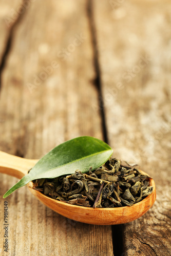 Green tea with leaf in spoon on old wooden table