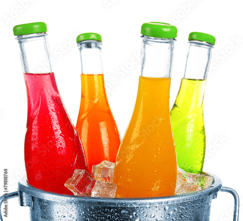 Bottles of tasty drink in metal bucket with ice isolated