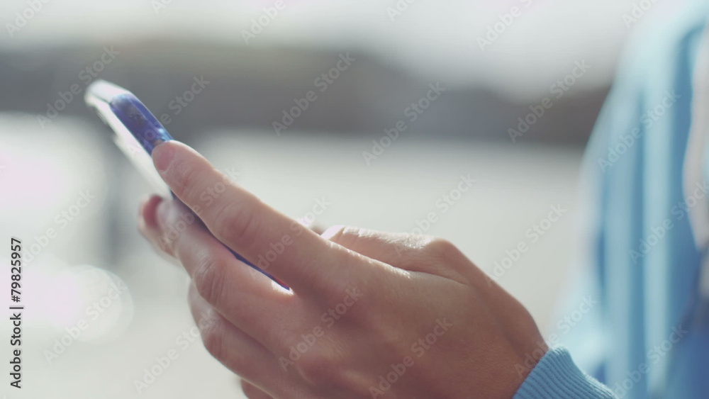 Female hands using a mobile cell phone by a river Female hands using a mobile cell phone by a river