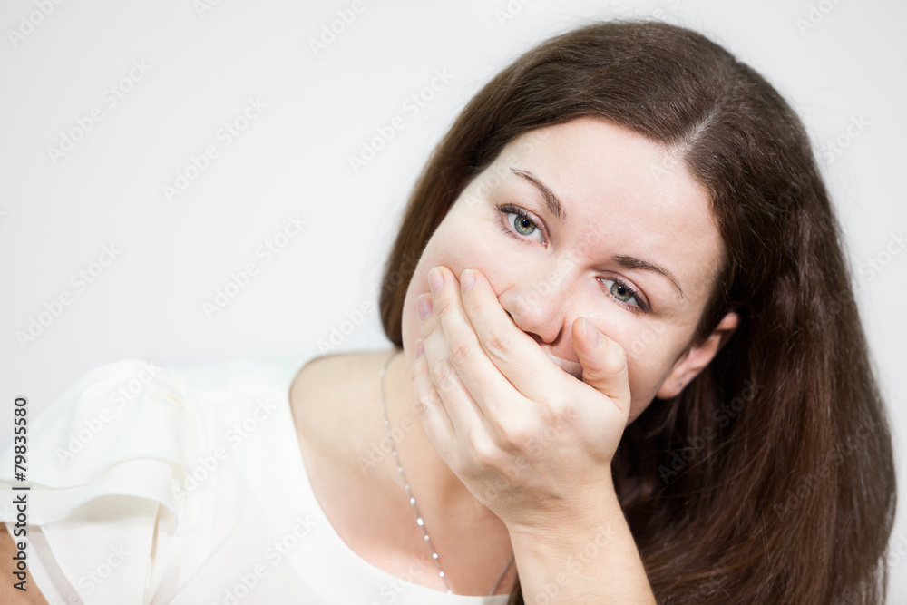 Caucasian young woman covering her mouth with hand Caucasian young woman covering her mouth with hand