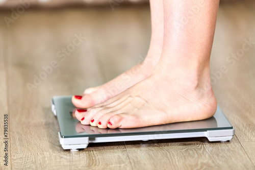 Close up of Caucasian woman with bare feet is on floor scales photo