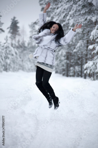 young woman is jumping in winter forest