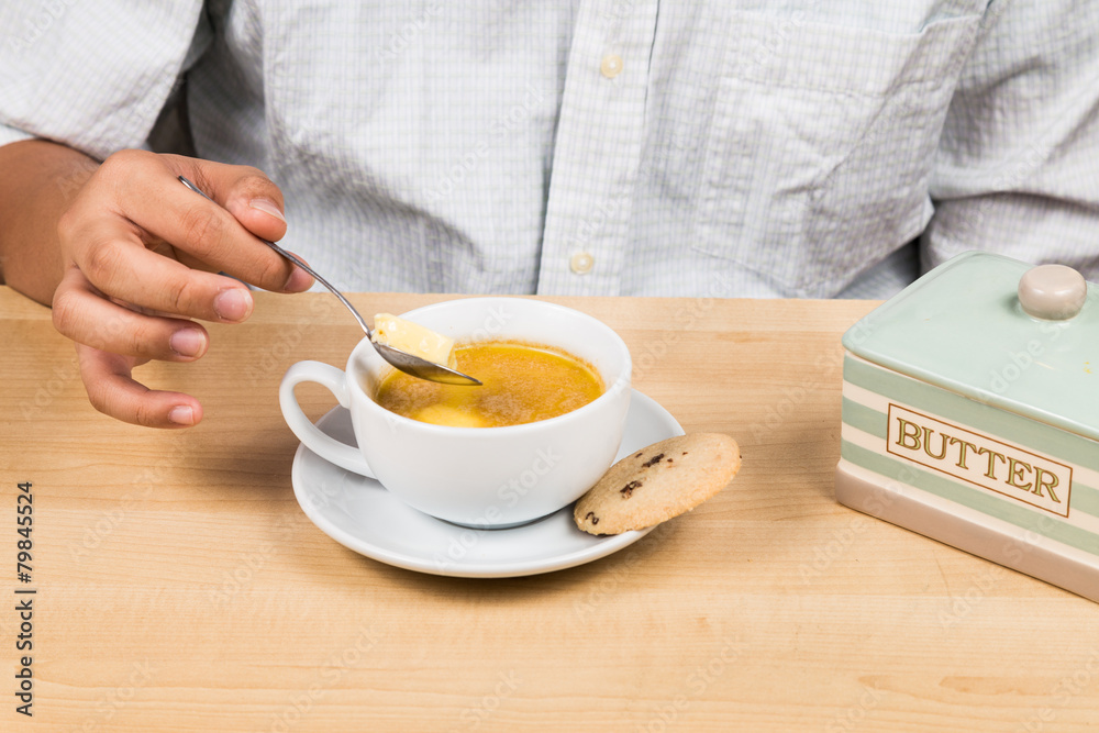 Person adding butter to coffee Person adding butter to coffee