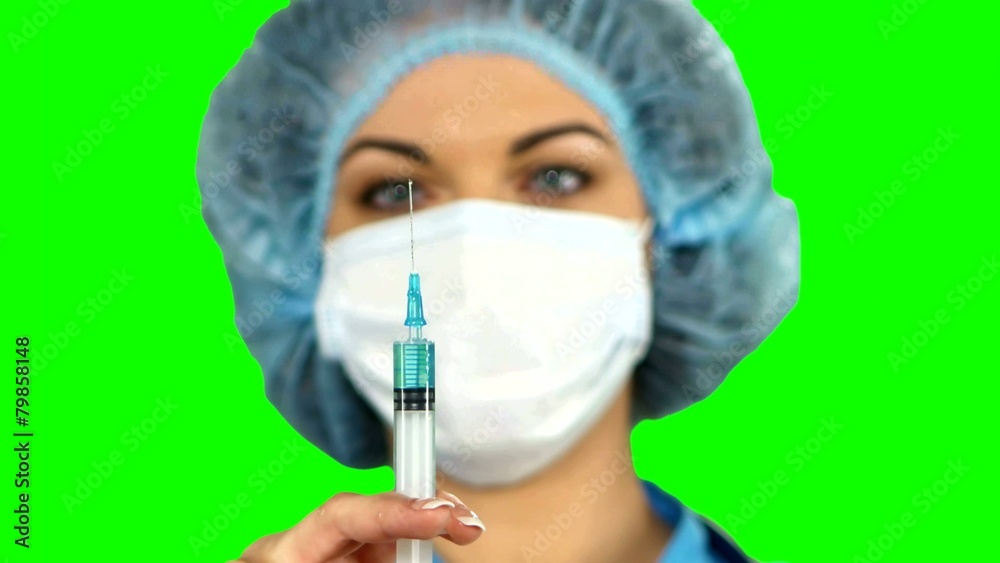 Young nurse in mask with syringe on green screen. Young nurse in mask with syringe on green screen.