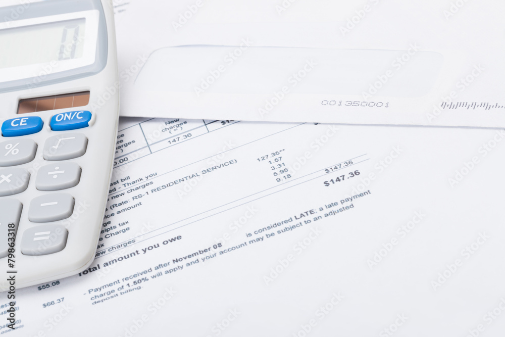 Calculator with utility bill under it - studio shot Calculator with utility bill under it - studio shot