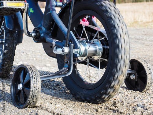 Fototapeta Naklejka Na Ścianę i Meble -  Bicycle with supporting wheels stuck in loose gravel
