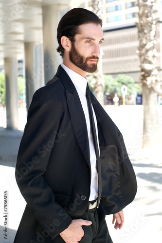 Young fashion man with beard walking outside in the city