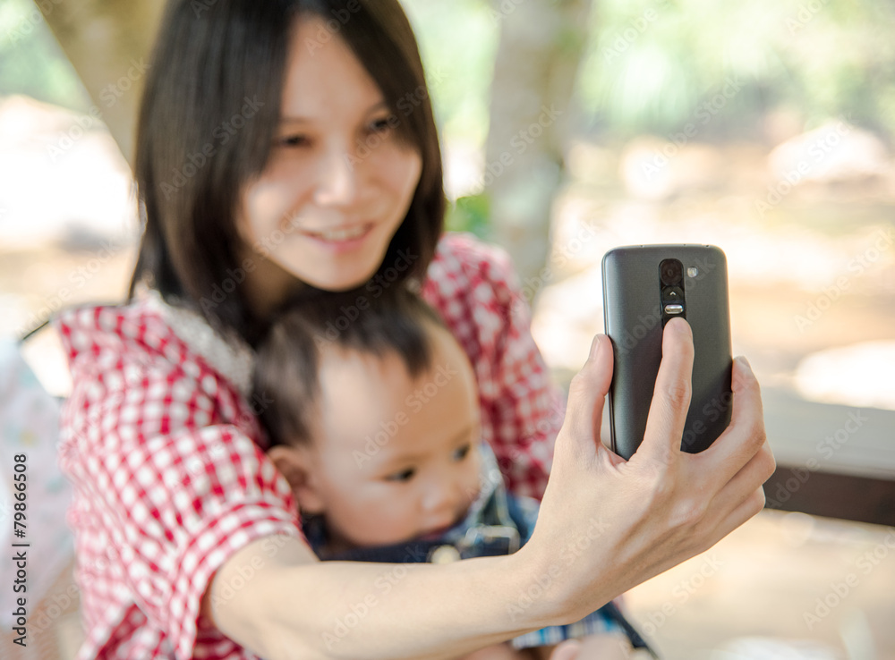 Fototapeta premium mother hold baby in arm taking selfie photo together 