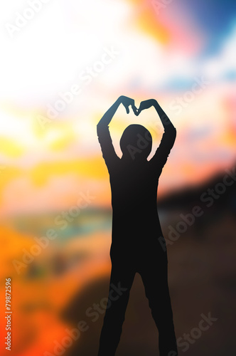 heart shape made with a girl arm at sunset ocean beach