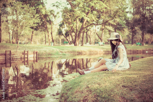 A cute Asian Thai girl is relaxing near the pond in the wilderne photo