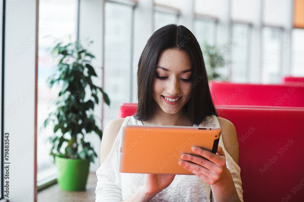 Beautiful girl working on a tablet and smiling Beautiful girl working on a tablet and smiling