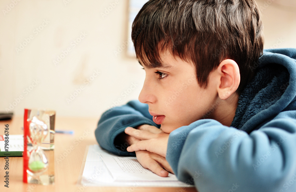 Obraz premium boy doing homework and looking on the hourglass
