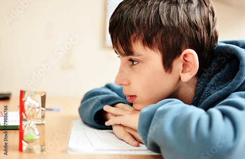 boy doing homework and looking on the hourglass