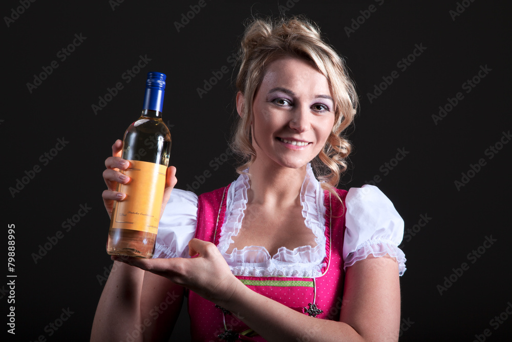 Blonde Hübsche Frau im Dirndl hält lächelnd Weinflasche Porträt Blonde Hübsche Frau im Dirndl hält lächelnd Weinflasche Porträt