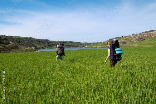 Men and girl with backpacks in deep green grass near sea © tns2710