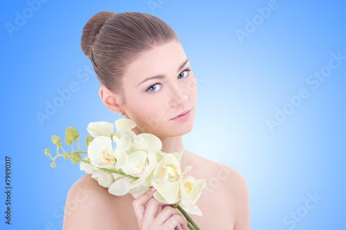 portrait of young beautiful woman with orchid flower over blue