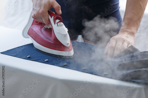 Man ironing his shirt photo