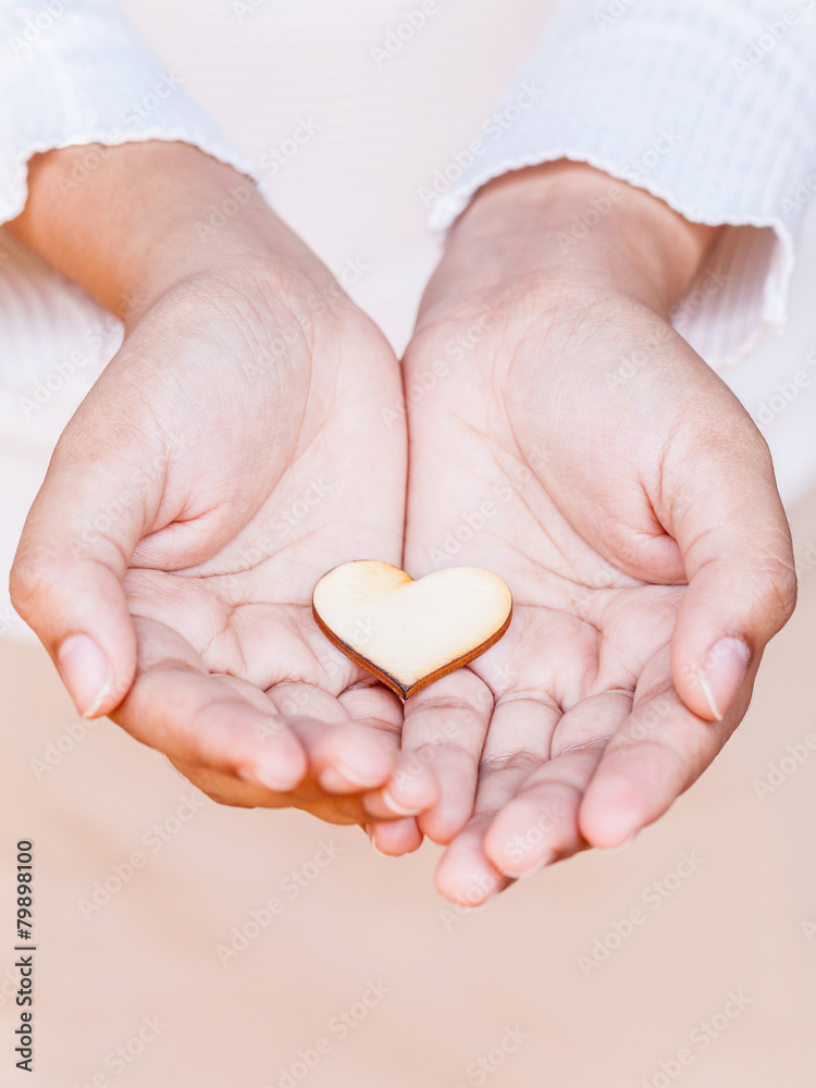 Obraz premium Girl holding wood shape of heart . Concept for giving love.