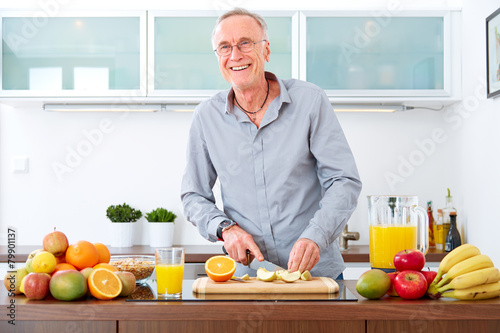 Mature man in the kitchen prepare fruits for breakfast.