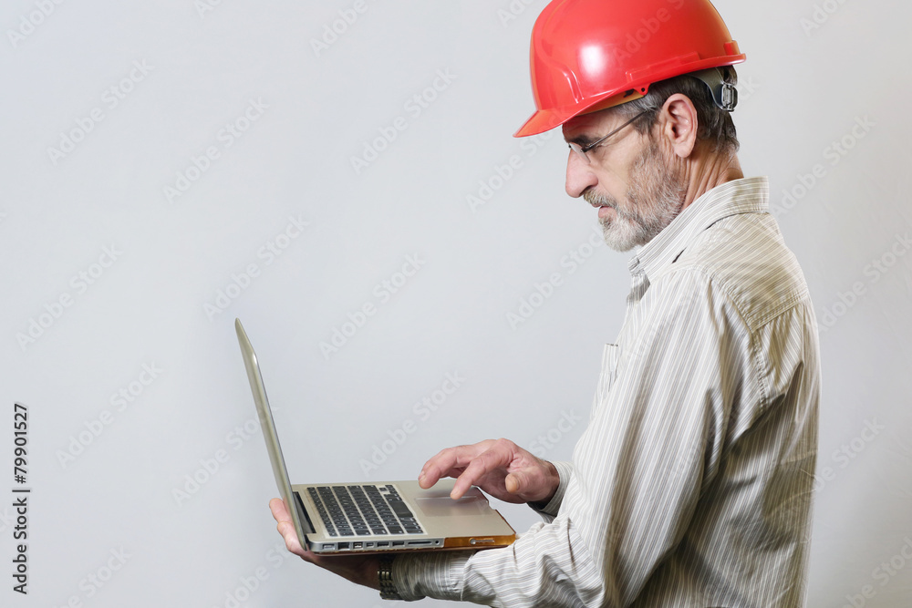 Portrait of an engineer with helmet and laptop, studio shoot