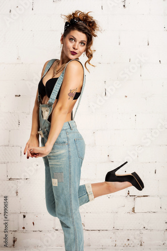 Swag woman in tattoos and overalls affectation