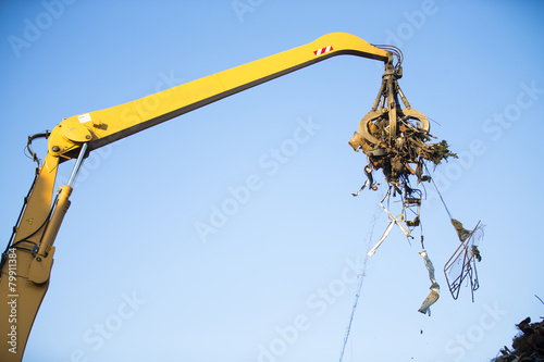Obraz na plátně Crane grabber loading metal rusty scrap in the dock