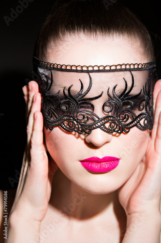 woman with pink lips and lace on black background. in studio