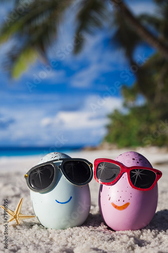 Happy easter eggs with sunglasses on ocean beach