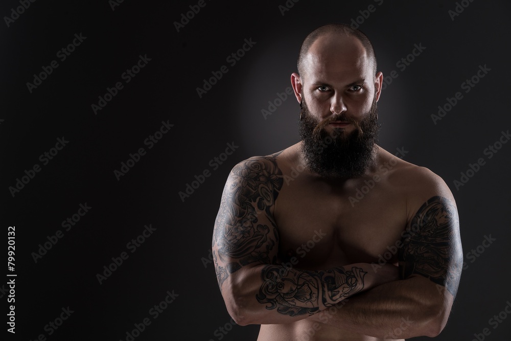 Upset muscular man with numerous tattoos