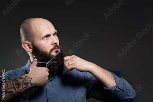 Man Cutting Beard against a grey background