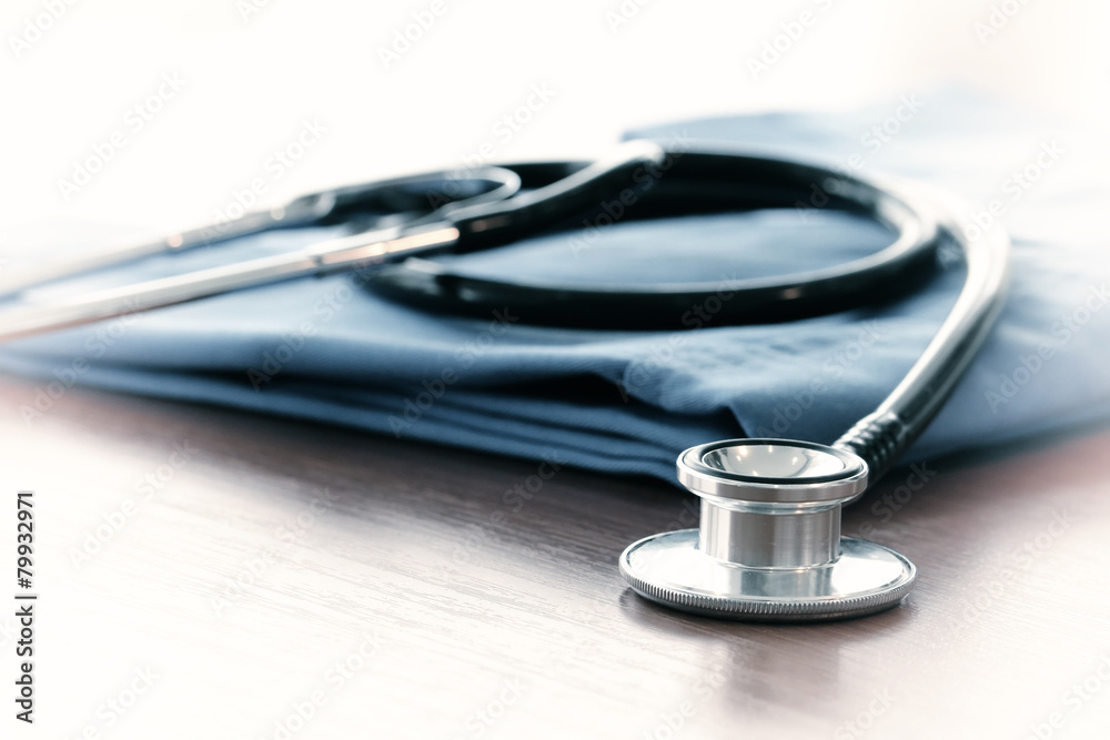 Stethoscope with blue doctor coat on wooden table with shallow D Stethoscope with blue doctor coat on wooden table with shallow D