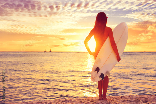 Surfer girl surfing looking at ocean beach sunset