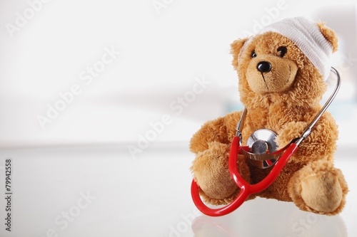 Obraz na płótnie Bandaged Teddy Bear on the Table with Stethoscope