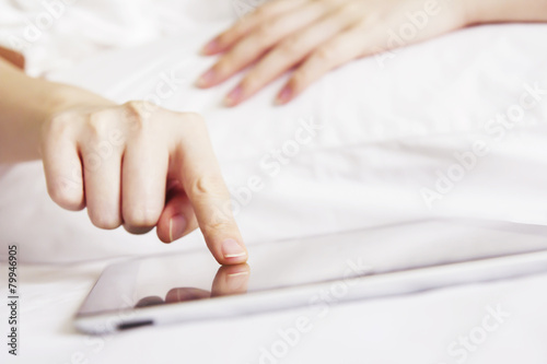 Cute young woman using digital tablet on the bed