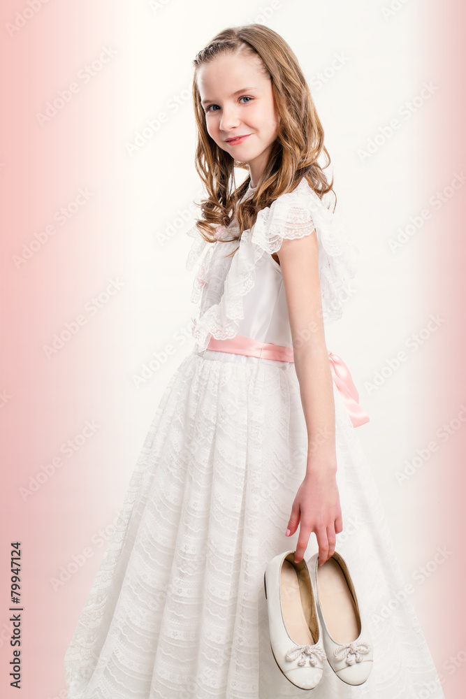 Naklejka premium Cute Communion girl holding shoes.