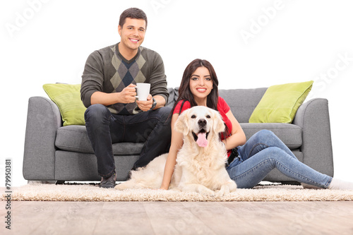 Young couple sitting with a dog on a modern sofa
