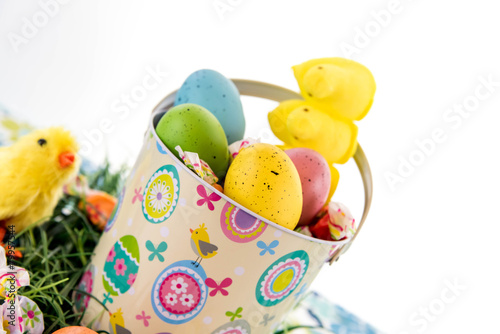 colored Easter eggs, yellow chicks, candy in a basket on grass © Casey E Martin