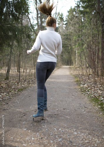 The woman jumps on the track in the early spring wood..