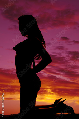 silhouette of woman in swimsuit kneeling hands on hips