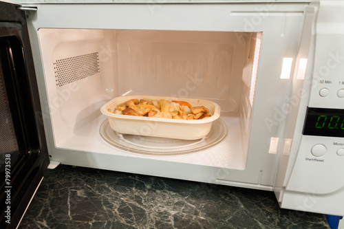 View of open microwave oven with delivery service food inside