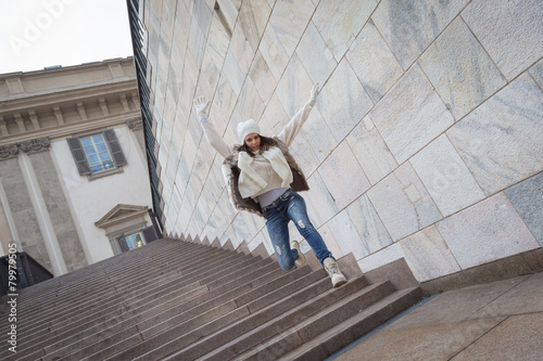 Beautiful young woman jumping down stairs
