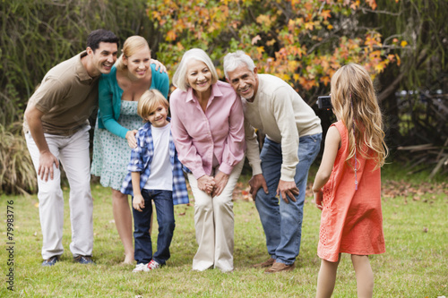 Girl taking picture of extended family in garden