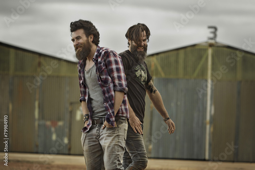 Two smiling men with full beards in abandoned landscape
