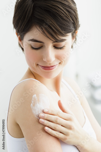 Germany, Bavaria, Munich, Young woman applying cream on hand, smiling