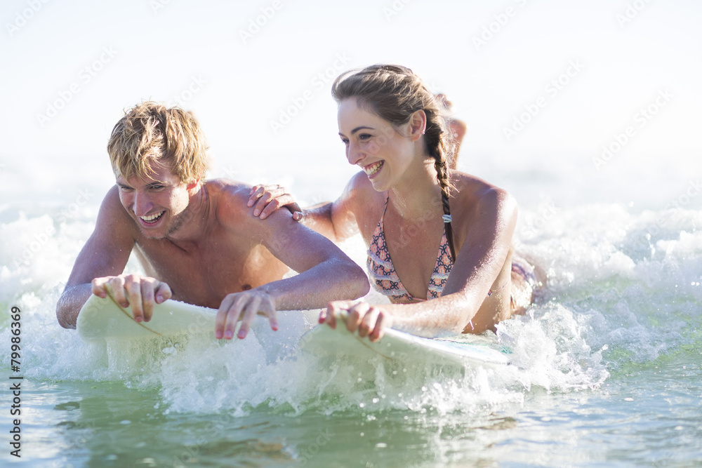Happy young couple lying on surfboards in the sea Happy young couple lying on surfboards in the sea