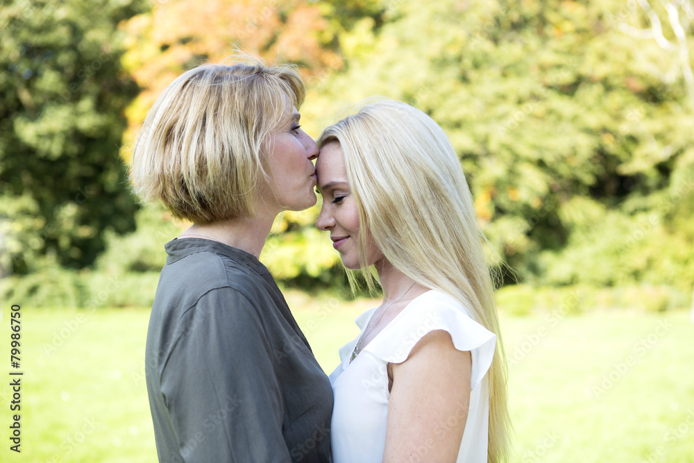 Mother kissing adult daughter in park